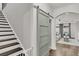 Inviting entryway with dark wood stairs, modern barn door, and an archway leading to a sunlit living area at 3968 Hanoverian Dr, Mount Pleasant, SC 29429