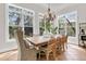 Sunlit dining area featuring a rustic wooden table, elegant chandelier, and lush outdoor views at 410 Ocean Oaks Ct, Kiawah Island, SC 29455