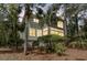 Rear exterior view of the beautiful home with big windows and surrounded by tall trees at 410 Ocean Oaks Ct, Kiawah Island, SC 29455