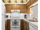 Cozy kitchen featuring wood cabinets, white appliances, and unique wallpaper trim at 4338 Sea Forest Dr, Kiawah Island, SC 29455