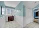 Bright bathroom with wainscoting, dark vanity, window, and access to additional rooms at 4584 Olde Smoak House Rd, Meggett, SC 29449