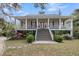 Inviting two-story home featuring a spacious wrap-around porch, stairs to the entrance, and meticulously maintained landscaping at 4584 Olde Smoak House Rd, Meggett, SC 29449