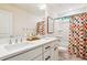 Bright bathroom with double sink vanity, black hardware, and colorful shower curtain at 5035 Gum Tree Ln, Johns Island, SC 29455