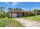 A brick home with a long driveway, an attached garage, and mature trees at 65 University Dr, Ladson, SC 29456