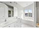Bright bathroom featuring double sinks, a large mirror, soaking tub, and tiled floors at 712 Bent Hickory Rd, Charleston, SC 29414