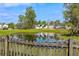 Scenic view of a pond reflecting neighborhood homes, as seen from behind a rustic wooden fence at 712 Bent Hickory Rd, Charleston, SC 29414