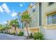 Colorful townhome exterior featuring private garages, and lush tropical landscaping with palm trees at 1011 Lighterman Way, Charleston, SC 29412