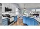 Open-concept kitchen boasts blue cabinetry, subway tile, and stainless steel appliances, flowing into the dining area at 117 Back Tee Cir, Summerville, SC 29485