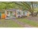 Quaint white brick home featuring a charming front porch and lush landscaping with a large shade tree at 1188 Camden St, North Charleston, SC 29405