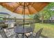 Outdoor patio with a dining table, chairs, grill, and umbrella in a lush green backyard at 1310 Belhaven Dr, Mount Pleasant, SC 29466