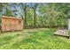 View of a backyard with a storage shed, wooden deck, fire pit and mature trees at 1708 Eallystockert Rd, Charleston, SC 29414