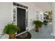 Close-up of a classic black front door adorned with potted plants, enhancing curb appeal and elegance at 1749 James Basford Pl, Mount Pleasant, SC 29466