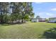 Open backyard showing large shade trees, storage buildings and other features of the property at 217 Mini Farm Rd, Bonneau, SC 29431