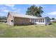 Brick home's rear exterior with a sunroom addition, metal roof, and ample green space at 217 Mini Farm Rd, Bonneau, SC 29431
