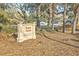 Beach House property sign nestled among trees and fallen leaves, marking private property at 26 Edgewater Aly, Isle of Palms, SC 29451
