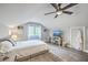 A modern bedroom with light gray walls and wood floors, featuring a ceiling fan and large window at 26 Edgewater Aly, Isle of Palms, SC 29451