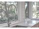 Modern kitchen sink and faucet set against a backdrop of lush greenery visible through the windows at 26 Edgewater Aly, Isle of Palms, SC 29451
