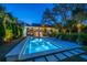 Twilight view of a backyard pool surrounded by lush landscaping and lounge chairs at 2629 Goldbug Ave, Sullivans Island, SC 29482