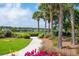 Picturesque community lake view with a landscaped walking path and tropical palm trees at 2743 Calico Bass Ln, Johns Island, SC 29455