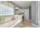 Elegant bathroom featuring a soaking tub, tiled floors, and a decorative window at 3023 Macbeth Creek Dr, Charleston, SC 29414