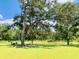 Lush backyard with patio furniture under a large tree, Adirondack chairs by the pond, and green grass at 3025 Dewitt Ct, Hollywood, SC 29449