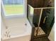 Modern bathroom with a shower featuring black tile, a glass partition, a soaking tub, and a window view at 3025 Dewitt Ct, Hollywood, SC 29449