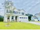 Charming two-story white home boasts a well-manicured lawn, black shutters and a two-car garage at 3025 Dewitt Ct, Hollywood, SC 29449