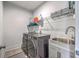 Well-equipped laundry room with modern washer and dryer, sink with cabinet, and shelving for storage at 3119 Sturbridge Rd, Mount Pleasant, SC 29466