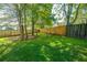 Lush green backyard featuring a vibrant lawn, trees, and a wooden fence at 3363 Kinross Ct, Summerville, SC 29485