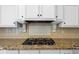 Close up of the kitchen's gas cooktop nestled in granite countertops and white custom cabinetry at 349 Mentor Rd, Summerville, SC 29483