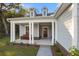 Inviting covered front porch with stately columns, bench seating and view of the wooden entry door at 4263 Hugh Bennett Dr, Johns Island, SC 29455