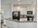 Well-lit kitchen boasts white cabinets, black appliances, mosaic tile backsplash, and granite countertops at 7638 Haywood St, North Charleston, SC 29418