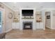 Cozy living room featuring a fireplace with a television, built-in shelving, and beautiful hardwood floors at 1010 Deep Gap Rd, Ridgeville, SC 29472