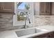 A kitchen sink with tiled backsplash sits beneath a window offering natural light and pleasant outdoor views at 11 Harleston Pl, Charleston, SC 29401