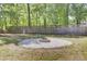 Backyard featuring a stone fire pit, gravel, lush greenery, and a wooden fence for relaxation at 116 Trestlewood Dr, Summerville, SC 29486