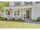 Charming front porch with rocking chairs, an American flag, and colorful flower planters at 116 Trestlewood Dr, Summerville, SC 29486