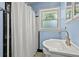Bathroom with blue walls, black and white tile, a sink with gold fixtures, and a window that provides natural light at 1211 Eastwood Ave, Hanahan, SC 29410