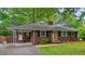 Exterior view of a red brick house featuring a covered parking, yellow front door, well maintained yard and mature trees at 1211 Eastwood Ave, Hanahan, SC 29410