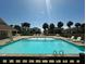 Large community pool with clear water, lounge chairs, and palm trees in the background at 126 Jungle Rd # 7B, Edisto Beach, SC 29438