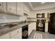 Well-lit kitchen with white cabinets, granite countertops, black appliances, and neutral flooring at 1307 Ventura Pl, Mount Pleasant, SC 29464