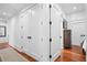 Hallway featuring hardwood floors, white walls, and a series of closets with dark hardware at 139 Tradd St # 2, Charleston, SC 29401