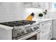Close-up of a kitchen with a stainless steel gas range, white cabinetry, and quartz countertops at 139 Tradd St # 2, Charleston, SC 29401