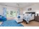 Bright bedroom featuring white wood-paneling, blue accents, tray ceiling, and French doors overlooking the outdoor greenery at 14 Royal Beach Dr, Kiawah Island, SC 29455