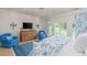Bright bedroom featuring white wood-paneling, blue accents, tray ceiling, and French doors overlooking the outdoor greenery at 14 Royal Beach Dr, Kiawah Island, SC 29455