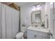 Bright bathroom with white vanity, marble countertop, gold trimmed mirror, and shower with striped curtain at 1535 Capel St, Mount Pleasant, SC 29466