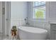 Close-up of a soaking tub, wainscoting, and floral wallpaper in the bathroom at 1535 Capel St, Mount Pleasant, SC 29466