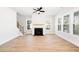 Open living room showcasing a fireplace, several windows, a ceiling fan, and beautiful wood flooring at 1577 Periwinkle Dr, Mount Pleasant, SC 29466