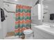 Small bathroom boasts colorful shower curtain, white vanity, and tiled shower space at 17 24Th Ave, Isle of Palms, SC 29451