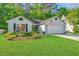 Inviting one-story home boasts a lush front lawn, colorful flower beds, and a classic American flag for added charm at 1722 S Nicole Pl, Charleston, SC 29414