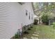 View of side yard with light siding, well-maintained gas meter, stepping stone pathway, and natural foliage at 227 Lipman St, Summerville, SC 29483